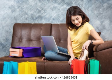 Young Beautiful Asian Woman Sitting On Sofa Shopping Online With Shopping Bags At Home.