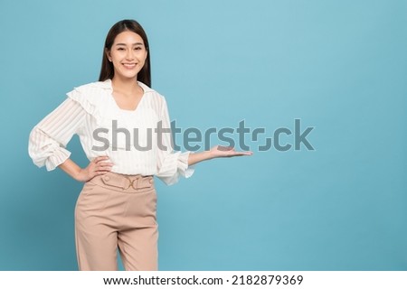 Young beautiful asian woman with smart casual cloth smiling and presenting copy space isolated on blue background