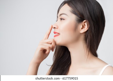 Young beautiful Asian woman with smiley face and red lips touching her nose.