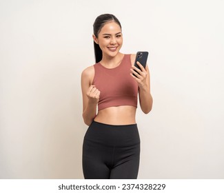 Young beautiful asian woman with sportswear using smartphone on isolated white background. Attractive Portrait latin sporty woman standing pose holding cell phone exercise workout in studio. - Powered by Shutterstock