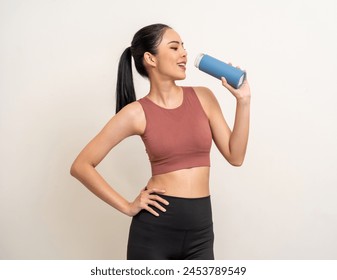 Young beautiful asian woman in sportswear holding bottle of water on isolated background. Portrait happy healthy slim fit and firm latin attractive sporty woman drinking water after exercise workout - Powered by Shutterstock