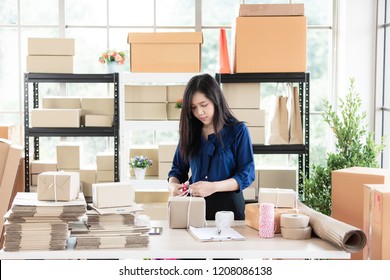 Young And Beautiful Asian Woman Standing Among Several Boxes And Checking Parcels, Working In The House Office. Concept For Home Base Business And Startup Ownership.