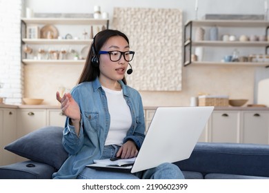 Young beautiful asian woman studying remotely sitting in living room on sofa, female student using headset and laptop for online distance learning and video call, teenager wearing glasses and shirt - Shutterstock ID 2190602399