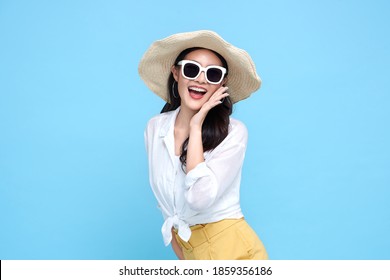 Young beautiful Asian woman in summer casual clothes wearing straw hat, sunglasses say something and hand side mouth and smile on isolated  bright blue backgroud.