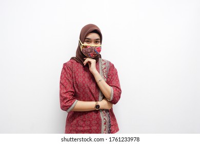 Young Beautiful Asian Woman That Wears Hijab And Batik Is Smiling And Doing Some Pose On White Background. And Also She Wears Batik-pattern Mask And Looks At The Camera