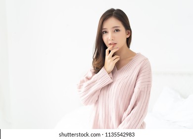 Young Beautiful Asian Woman In Warm Knitted Pink Clothes Holding Her Finger On Her Mouth At Home. Fashion Model. Autumn, Winter With Copy Space