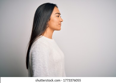 Young Beautiful Asian Woman Wearing Casual Sweater Standing Over White Background Looking To Side, Relax Profile Pose With Natural Face With Confident Smile.