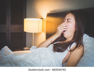 Young Beautiful Asian Woman Yawn And Feeling Sleepy On White Bed In Bed Room.