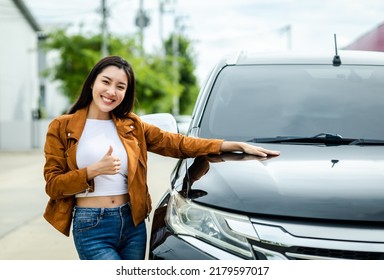 Young Beautiful Asian Women Buying New Car. She Was Standing In Near Car On The Roadside. Smiling Female Driving Vehicle On The Road On A Bright Day