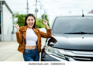 Young Beautiful Asian Women Buying New Car. She Was Standing In Near Car On The Roadside. Smiling Female Driving Vehicle On The Road On A Bright Day