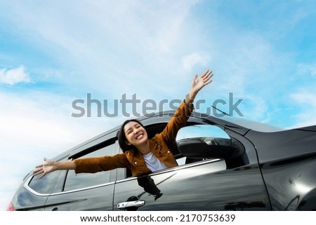 Young beautiful asian women getting new car. she very happy and excited. Smiling female driving vehicle on the road on a bright day. Sticking her head outta the windshield Foto d'archivio © 
