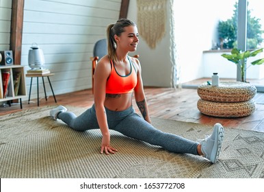 Young beautiful athletic girl in leggings and top sits on a twine. Healthy lifestyle. A woman goes in for sports at home. - Shutterstock ID 1653772708