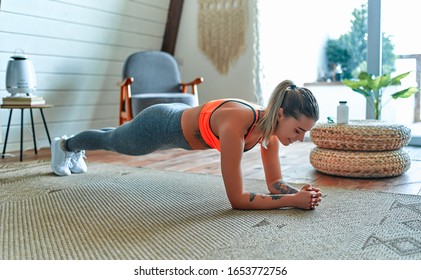 Young beautiful athletic girl in leggings and top makes an exercise plank. Healthy lifestyle. A woman goes in for sports at home. - Shutterstock ID 1653772756