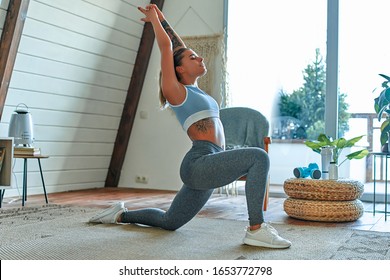 Young beautiful athletic girl in leggings and top makes lunges. Healthy lifestyle. Woman doing exercises at home. - Shutterstock ID 1653772798