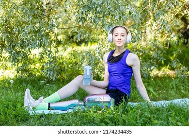 Young beautiful athletic woman with bionic prosthetic leg doing sport exercises in the park outdoors in summer. Concept of active lifestyle of disabled people. Listening to music, drinking water - Powered by Shutterstock