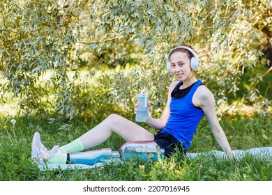 Young beautiful athletic woman with bionic prosthetic leg doing sport exercises in the park outdoors in summer. Concept of active lifestyle of disabled people. Listening to music, drinking water - Powered by Shutterstock