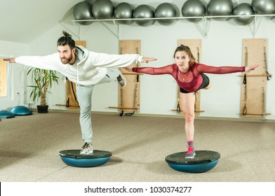 Young beautiful and attractive fitness couple workout on their balance by standing on the half ball on the one leg - Powered by Shutterstock