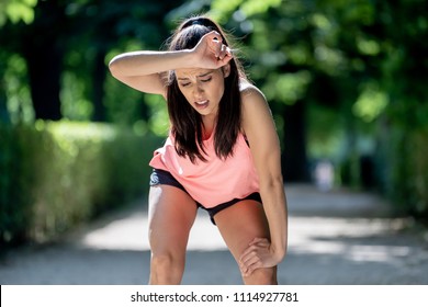 young beautiful and attractive sport woman in runner sportswear breathing gasping and taking a break tired and exhausted after running workout on Autumn urban city forest park in fitness concept
