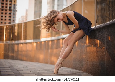 Young Beautiful Ballerina In Black Dress And Pointe Shoes Dancing Outdoors In A Modern Environment. Ballerina Project.