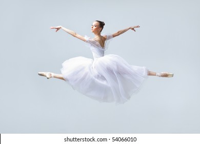 young beautiful ballerina posing in front of gray studio background