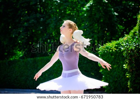 Young beautiful ballerina with two white birds dove of peace in a city park