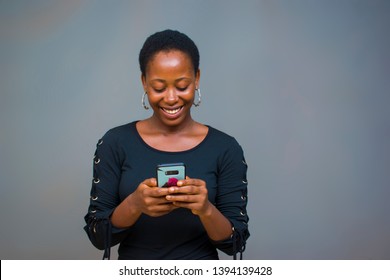 young beautiful black lady smiling and pressing her phone