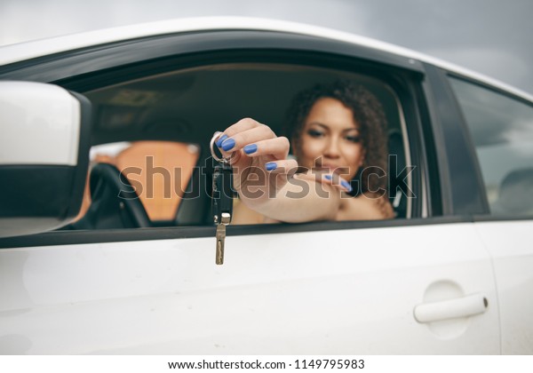 Young beautiful black teenage driver holding car keys\
driving her new car