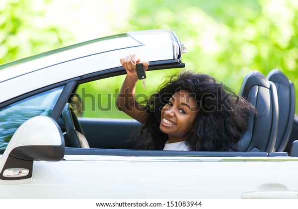 Young beautiful black teenage driver holding car keys\
driving her new car