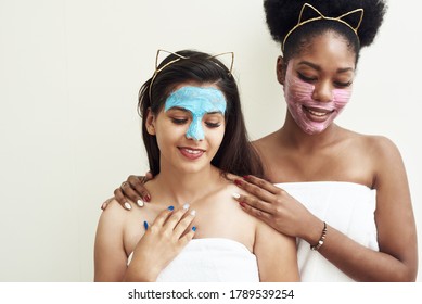 Young beautiful black woman and her cute friend smiling, hugging in moisturizing and anti-aging masks. End of home skin care, girlfriends and love - Powered by Shutterstock