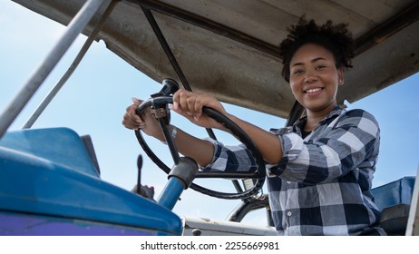 Young beautiful black woman working on a tractor in the corn field gender equality concept. Smart female farmer agriculture in farmland. - Powered by Shutterstock