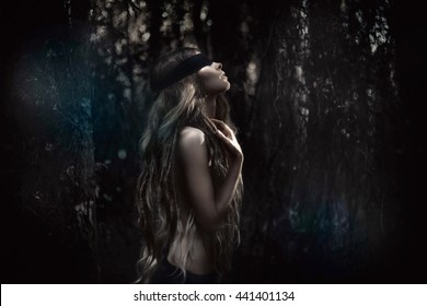Young beautiful blindfolded woman in forest