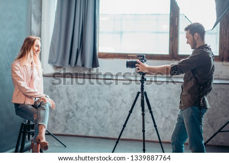 Young beautiful blond model posing in chair for a professional photographer at the studio, side view photo . job, profession
