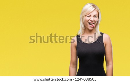 Young beautiful blonde attractive woman wearing elegant dress over isolated background sticking tongue out happy with funny expression. Emotion concept.