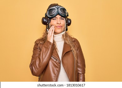 Young Beautiful Blonde Aviator Woman Wearing Vintage Pilot Helmet Whit Glasses And Jacket Touching Mouth With Hand With Painful Expression Because Of Toothache Or Dental Illness On Teeth. Dentist