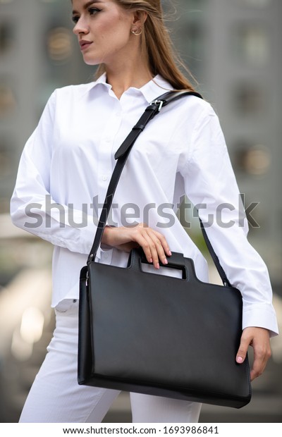 Young\
beautiful blonde business lady in classic look walking on the\
street with Briefcase Designer Leather Laptop Satchel Portfolio\
Messenger Bag.  different color of bag and no\
logo.