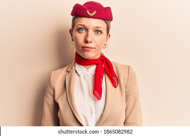 Young Beautiful Blonde Girl Wearing Stewardess Uniform With Serious Expression On Face. Simple And Natural Looking At The Camera. 