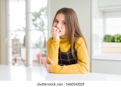 Young Beautiful Blonde Kid Girl Wearing Casual Yellow Sweater At Home Looking Stressed And Nervous With Hands On Mouth Biting Nails. Anxiety Problem.