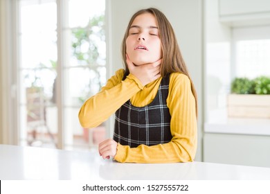 Young Beautiful Blonde Kid Girl Wearing Casual Yellow Sweater At Home Touching Painful Neck, Sore Throat For Flu, Clod And Infection