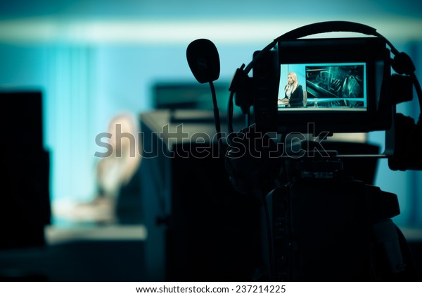 Young beautiful blonde television announcer at studio during live broadcasting.Female TV director at editor in studio.Recording at TV studio with television anchorwoman. TV NEWS studio with camera 