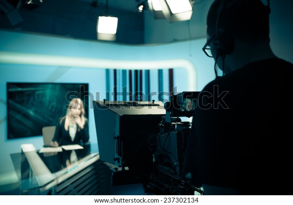 Young beautiful blonde television announcer at studio during live broadcasting.Female TV director at editor in studio.Recording at TV studio with television anchorwoman. TV NEWS studio with camera 