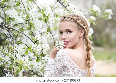 Young beautiful blonde woman in blooming garden. Bride. - Powered by Shutterstock