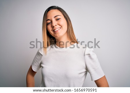 Young beautiful blonde woman with blue eyes wearing casual t-shirt over white background with a happy and cool smile on face. Lucky person.