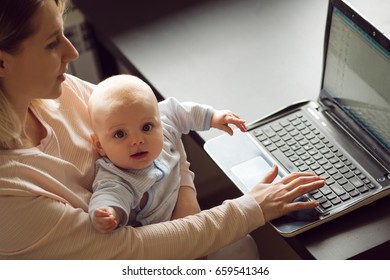 Young Beautiful Blonde Woman, Mother In Home Office With Computer And Her Baby. Work And Child Care.