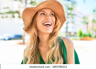 Young Beautiful Blonde Woman On Vacation Wearing Summer Hat Smiling Happy. Standing With Smile On Face At Street Of City.