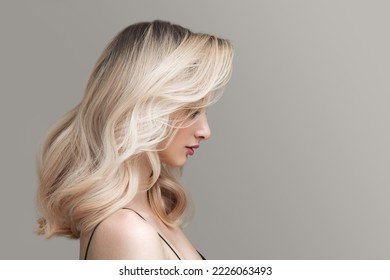 Young beautiful blonde woman on a gray background. Beautiful wavy shiny hair. - Powered by Shutterstock