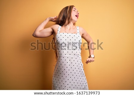 Young beautiful blonde woman on vacation wearing summer dress over yellow background stretching back, tired and relaxed, sleepy and yawning for early morning