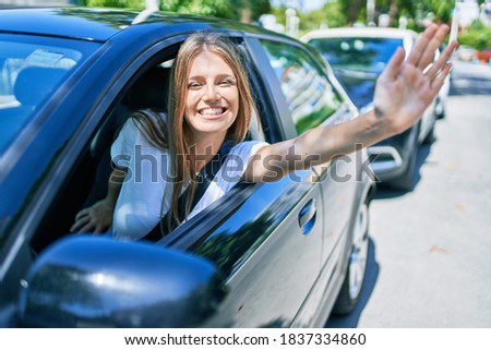 Young beautiful blonde woman smiling happy sitting at the car with hand out and cheerful expression