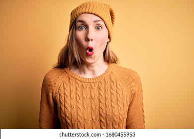 Young Beautiful Blonde Woman Wearing Casual Sweater And Wool Cap Over Yellow Background Afraid And Shocked With Surprise Expression, Fear And Excited Face.