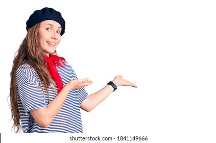 Young Beautiful Blonde Woman Wearing French Beret And Striped T-shirt Inviting To Enter Smiling Natural With Open Hand 