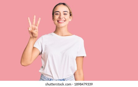 Young beautiful blonde woman wearing casual white tshirt showing and pointing up with fingers number three while smiling confident and happy.  - Shutterstock ID 1898479339